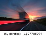 Small photo of Blurring. A large truck is driving along the highway at high speed. Sky with bright red clouds. Delivery of cargo.