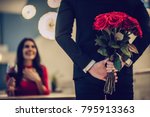 Beautiful loving couple is spending time together in modern restaurant. Attractive young woman in dress and handsome man in suit are having romantic dinner. Celebrating Saint Valentine's Day.