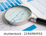 Small photo of Magnifying glass on chart graph spreadsheet paper. Financial development, Banking Account, Statistics, economy, Stock exchange trading, Business office company meeting concept.