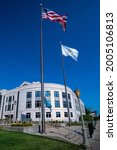 Small photo of Edwardsville, IL—July 7, 202; Low angle view of American and Illinois state flag flying in front of the Madison County Administrative Building in southern Illinois in summer