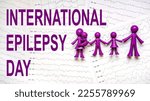 Small photo of International Epilepsy Day, Epilepsy awareness. Purple toy adults and kids people, family and International Epilepsy Day text on brain wave on electroencephalogram EEG for epilepsy