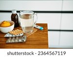 Natural and medical cold and flu remedies on table at home. Cold and flu influenza fall autumn and winter season. Cup with hot tea, lemon, thermometer pills and capsules