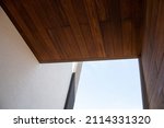 Modern architecture detail of wooden facade cladding, white wall and sky background