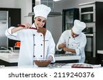 Small photo of latin woman pastry chef wearing uniform holding a bowl preparing delicious sweets chocolates at kitchen in Mexico Latin America
