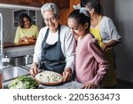 Hispanic women family grandmother, mother and granddaughter cooking at home at kitchen in Mexico Latin America