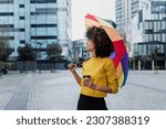 young African American woman homosexual with rainbow flag or umbrella in city of Latin America, Hispanic and caribbean LGBT female with afro hair 