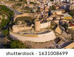 Aerial panoramic view of medieval Elda castle above the town with partially restored walls, towers and gate made of white lime stone in Spain