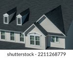 Small photo of Close up view of modern single family house details with horizontal vinyl siding, accented window frame, double gable, two pedimented dormer windows on the roof
