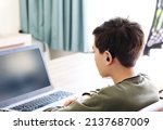 Small photo of Deaf teenager boy Wearing Hearing Aid using Laptop. Disable student with disabilities deafness distancing learning online from home.