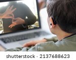Small photo of Deaf teenager boy Wearing Hearing Aid using Laptop. Disable student with disabilities deafness distancing learning online from home making communication hands language with teacher via VDO call.