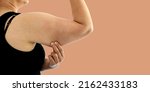 Small photo of A young Asian woman grabbing skin on her upper arm with excess fat isolated on a white background. Pinching the loose and saggy muscles. Overweight concept