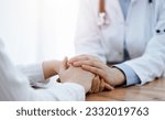 Small photo of Doctor and patient sitting at the wooden table in clinic. Female physician's hands reassuring woman. Medicine concept