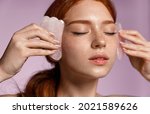 Small photo of Close up portrait of beautiful redhead girl, ginger female massaging face with jade scraper, close eyes, doing tcm cosmetology procedure, purple background