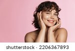 Small photo of Skin care. Woman with beauty face touching healthy facial skin portrait. Beautiful smiling girl model with natural makeup touching glowing hydrated skin on pink background closeup.