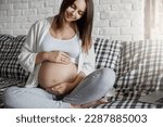 Small photo of Beautiful pregnant lady caring of her tummy listening for her fetus sitting home. Having a wealthy husband is a key to easy pregnancy.