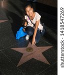 Small photo of Hollywood, California/USA: Jul 12-2014: Little latina Mexican girl enjoyng the street of fame in Hollywood and touching the star of Marylin Monroe on the floor