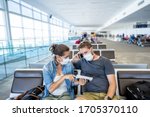 COVID-19 worldwide borders closures. Couple with face mask stuck in airport terminal after being denied entry to other countries. Passengers stranded in airport on his travel back to home country.