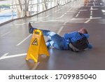 Small photo of Inattentive man has fallen down on wet floor in spite of the big yellow warning sign