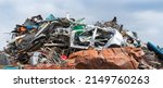 Small photo of Close-up of mixed scrap metal pile in junkyard on panoramic blue sky background. Colored jumble of iron waste as old car body, wire mesh or rusty sheet and various leftover recyclable materials. Dump.