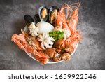 Seafood shrimps prawns squid mussels spotted babylon shellfish crab  on plate and dark background / Cooked food served seafood buffet concept 