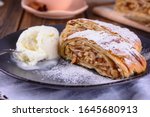 Pair pieces of delicious strudel stuffed with apples and cinnamon at a plate next to ice cream ball