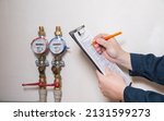 Small photo of A man writes down the readings of water meters with a pen on paper. The concept of paying for utilities. Rise in price per cubic meter of water, close-up