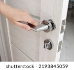 A man's hand opens an interior door with a broken doorknob. Poor quality door hardware, breakage, damage. Close-up