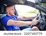 Small photo of Handsome frightened angry guy, driver, young scared man shocked about to have accident, driving car fast on road holding steering wheel of automobile. Unfastened by a seat belt. Traffic violation