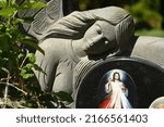 Small photo of Kitschy grave decorations with stone angels and an image of Jesus