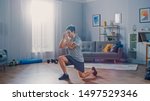 Strong Athletic Fit Man in T-shirt and Shorts is Doing Forward Lunge Exercises at Home in His Spacious and Bright Apartment with Minimalistic Interior.
