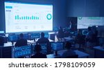Small photo of Team of Professional Big Data Business Traders Work on Desktops with Screens Showing Charts, Graphs, Infographics, Technical Neural Data and Statistics. Low Key Control and Monitoring Room.