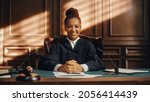 Small photo of Cinematic Court of Law Trial: Portrait of Impartial Smiling Female Judge Looking at Camera. Wise, Incorruptible, Fair Justice Doing Her Job Professionally, Sentencing Criminals and Protecting Innocent