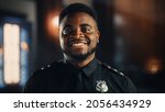 Small photo of Authentic Portrait of Happy and Handsome Black Policeman in Universal Uniform Smiling at Camera. Successful African American Law Enforcement Agent. Courtroom Security Guard at Work.