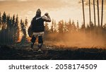 Small photo of Medieval Knight Looking at Sunrise. Romantic Hero, Soldier, Warrior in Body Armour with Sword On a Journey to Safe Princess. Mysterious Smoke, Magic Forest and Adventure. Back View Shot