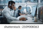 Small photo of Professional Investment Traders Talking into Headset, Working on Computer with Screen Showing Finance Statistics, Charts Strategy, Stock Market, Telemarketing. Big Office Call Center.