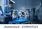 Small photo of Factory Office Facility: Chief Engineer Developer Holds Tablet Computer, Examins Augmented Reality Model of an Electric Generator. Modern Industry 4.0 Research and Development Center Concept.