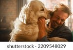 Small photo of Happy Handsome Young Man Play with Dog at Home, Gorgeous Golden Retriever. Attractive Man Sitting on a Floor. Excited Dog Licking the Owner that Teases the Pet. Having Fun in the Stylish Apartment.