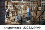 Small photo of Establishing Shot of Multicultural Team of Warehouse Workers at Work in Internet Shop's Storeroom. Small Business Owners and Inventory Managers Working on Laptop, Tablet, Packing Parcels for Delivery.