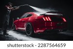 Small photo of Car Wash Expert Using Water Pressure Washer to Clean a Red Modern Sportscar. Adult Man Washing Away Dirt, Preparing an American Muscle Car for Detailing. Creative Cinematic Footage with Luxury Vehicle