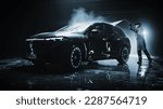 Small photo of Advertising Style Photo of a Professional Car Wash Specialist Using a High Pressure Washer to Clean and Prepare a High Tech Black Family Electric SUV for Detailing, Polishing and Waxing