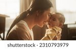 Small photo of Motherly Affection Concept: Close Up Portrait of an Affectionate Asian Mother Touching Noses with her Baby in a Cosy Naturally Lit Bedroom. Warm Atmosphere Reflecting the Heartwarming Moment