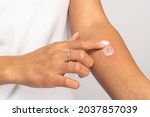 Small photo of Allergic reaction, itch, allergy, dermatiti concept. Close up of woman applying cream or ointment on swell skin after insect mosquito bites, isolated on grey studio background.