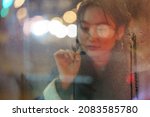 Young melancholic woman draw heart on steamy wet window think of boyfriend and love relationship. Pensive asian girl has melancholy feelings feel lonely and unhappy. Healthbreak and solitude concept