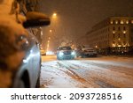Transport collapse on road at night during winter snowfall, snow blizzard causes huge traffic jam in European city, snowy road with many cars stacked on road, evening roadway in snowstorm