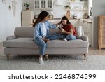 Small photo of Caring attentive mother stroking daughter sits on couch with phone in hands offers to take walk and spend time together. Kind woman works as nanny looking after teenage girl during absence of parents