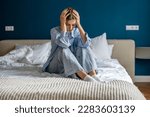 Small photo of Upset depressed woman sitting on bed hold head in hands lost in thoughts thinking of problem solution. Worried devastated unhappy young female suffering from personal trouble need psychological help