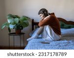 Small photo of Upset depressed teen girl sitting on bed next to smartphone, feeling lonely and frustrated, sad teenager suffering from online bullying. Depression and teen use, cyberbullying concept