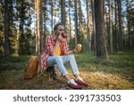 Small photo of Camper man eating sandwich drinking tea on halt in forest enjoying nature sitting on stump. Guy hiker having break resting in woodland, mountains. Outdoors activity, camping, hiking, trekking concept.