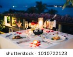 Luxury romantic candlelight dinner table setup for couple in ocean view restaurant on Valentine's day with Champaign & wine glasses and beautiful food decoration.  