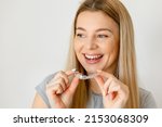 Small photo of Beautiful cheerful woman is holding an invisalign bracer in a studio with white background
